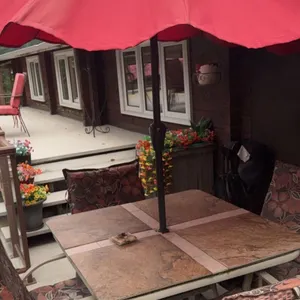 Patio Dining Set with Stone-Top Table, Four Cushioned Chairs, and Red Umbrella