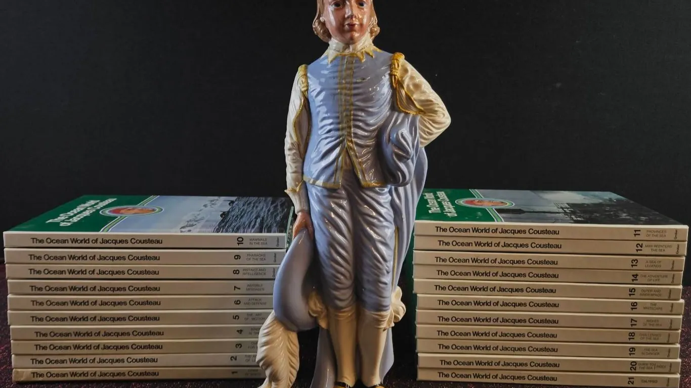 21 'The Ocean World of Jacques Cousteau' Books and Porcelain Boy Figurine