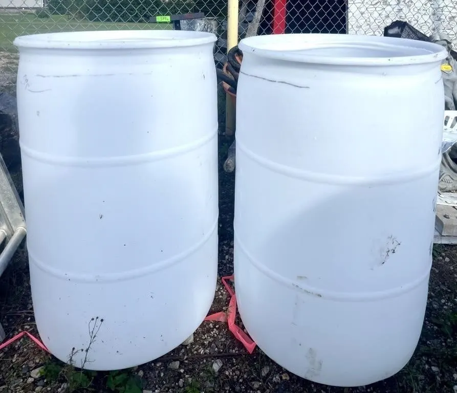 Pair of white 50 gallon water barrels.