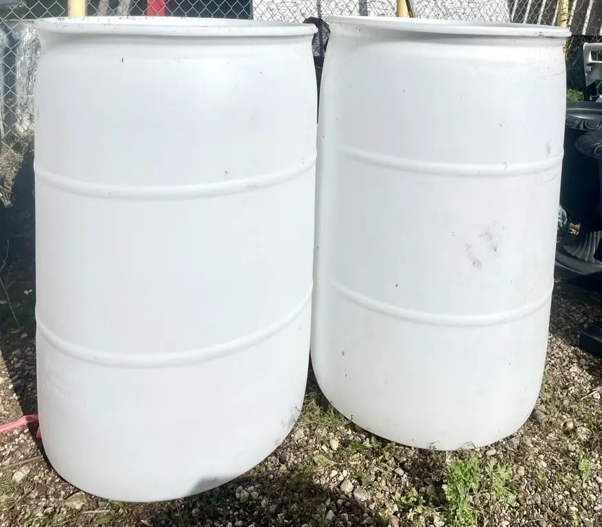 Pair of white 50 gallon water barrels.