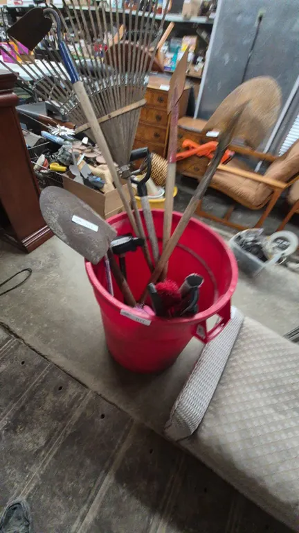 Assorted Garden Tools: Rakes, Shovels, Spades, and Brushes in Red Bucket