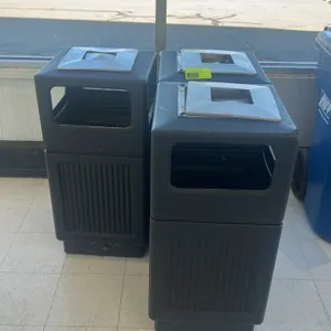 Commercial trash receptacles. Features black molded polyethylene construction, side waste disposal openings, vertically fluted lower panels, and integ