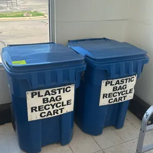 Poly recycling bins. Features blue molded polyethylene construction, hinged lids, integrated handles, and rear wheels. Each labeled "Plastic Bag Recyc