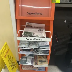 Poly multi-tier newspaper merchandiser. Features orange molded polyethylene body, upper clear display window, and tiered white wire display racks. Con