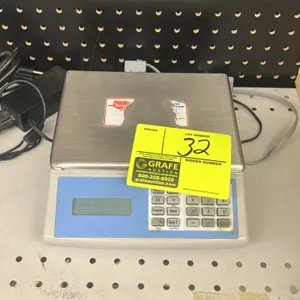 Digital bench scale. Features stainless steel weighing platform, digital display, numeric keypad, and external AC power adapter.