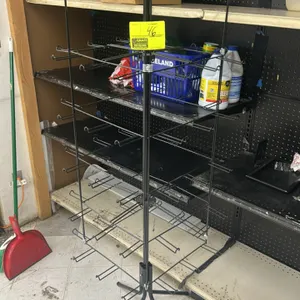 Metal 4-sided multi-tier merchandiser display rack. Features black wire construction with multi-tier hanging display hooks on four sides. Mounted on a