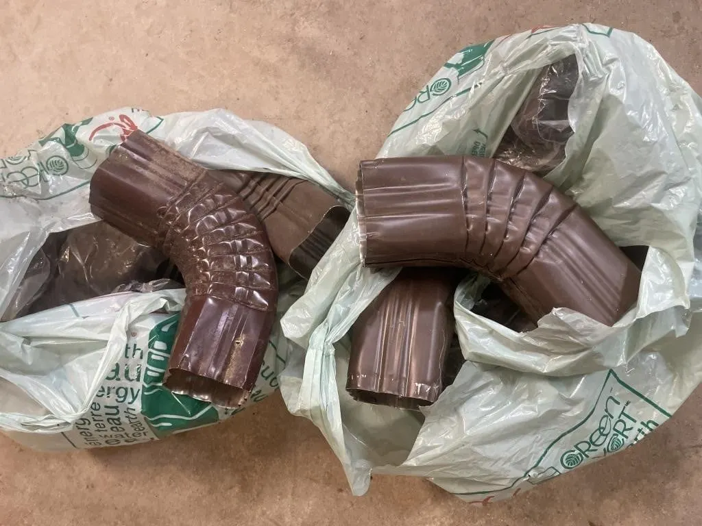 Two bags wit a dozen brown aluminum drainpipe
