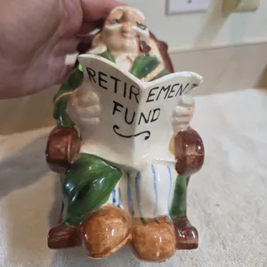 Vintage left in japan. Ceramic retirement piggy bank shaped like old man and green robe reading in a