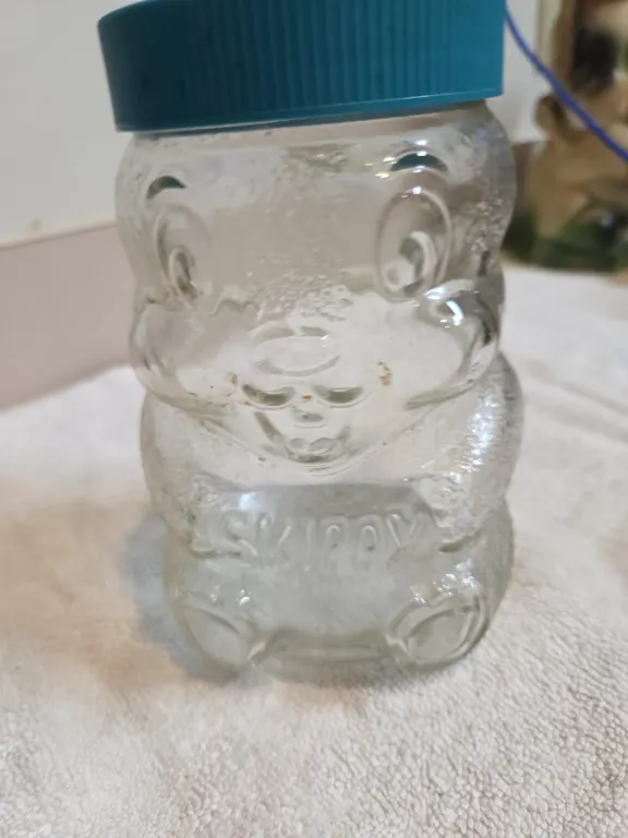 Vintage 1990s, Skippy, peanut butter glass jar coin. Bake shaped like a bear with teal. Plastic lid.
