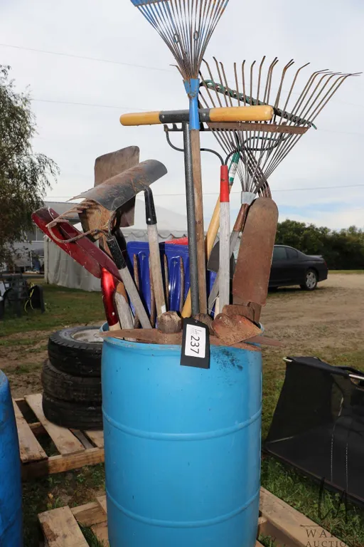 Rain barrel with large selection of rakes, shovels, picks etc.