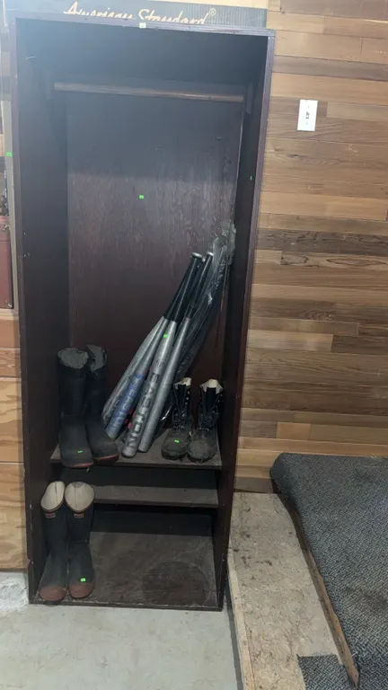 Wooden Locker with Storage Shelf, Rubber Boots, Work Boots, and Aluminum Baseball Bats