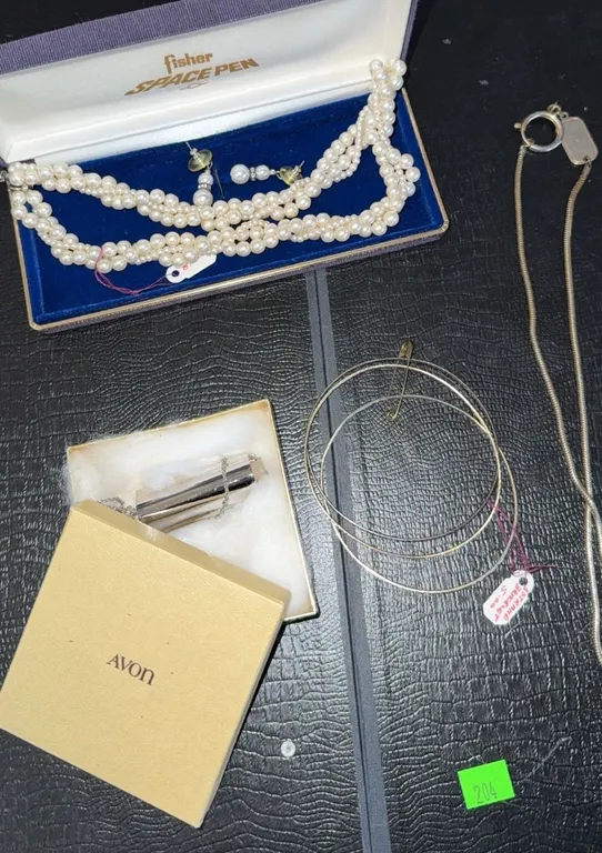 Jewellery and Writing Lot Including Faux Pearl Necklace, Avon Pendant, Bangles, Space Pen Case