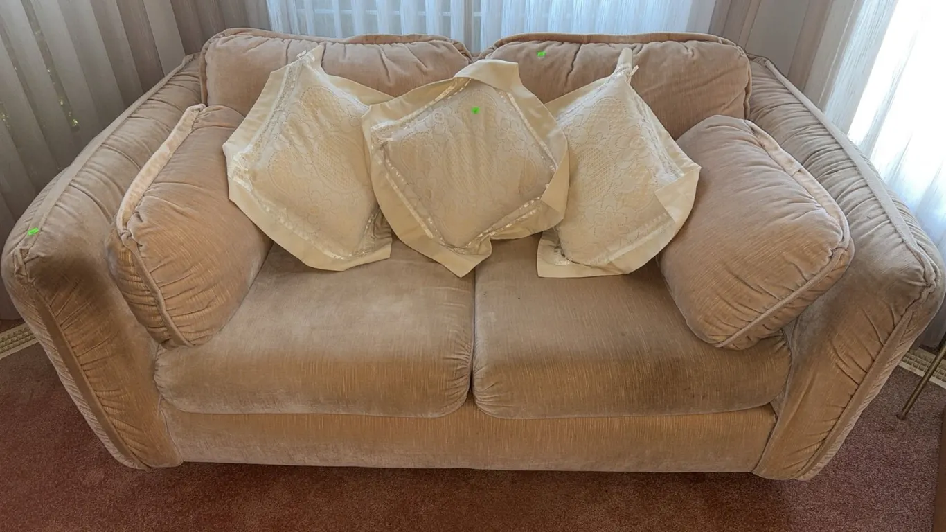 Beige Upholstered Loveseat With Four Cream Patterned Throw Pillows