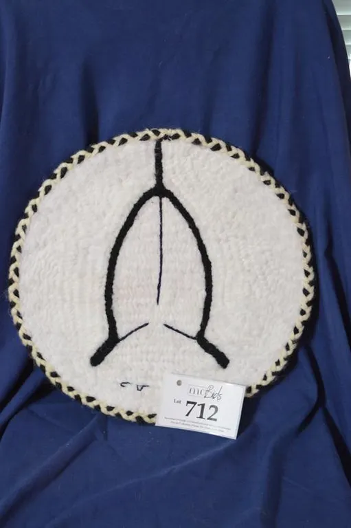 Drum Shape Hanging With Steel Ring, White Wool Background And Black Wool Fishing Spear In Center.