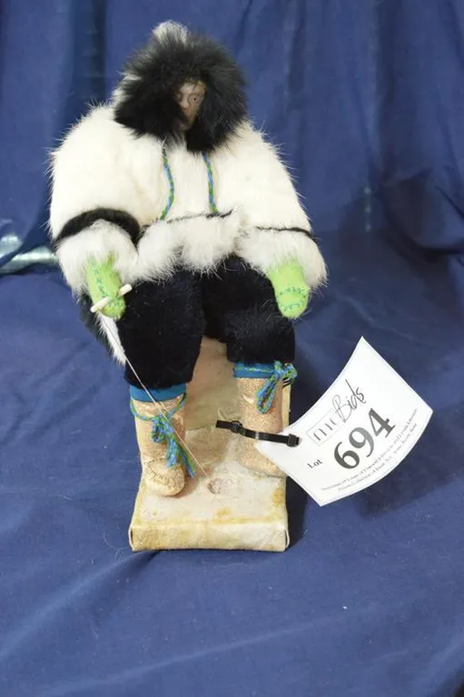 Fishing Man Doll In Traditional Parka, Pants And Boots Sitting On Two Caribou Bones.