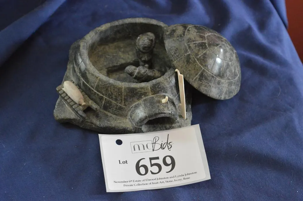 Igloo With Two Inuit. One Sitting On Sleeping Shelf, Second Bent Over Working.