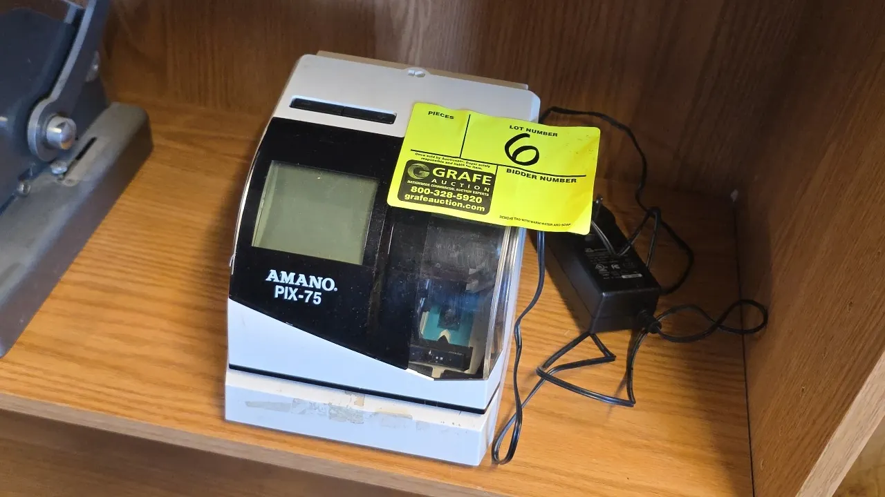Amano PIX-75/A187 electronic time card machine. Features digital LCD screen and top/side punch slot. S/N: 153907. Includes external AC switching power