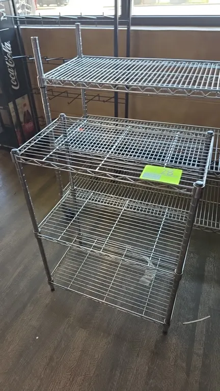 Metro 3-tier metal wire shelving rack. Features three wire shelves and four upright support posts. 24" x 13" x 30". Mounted on leveling feet. Backgrou