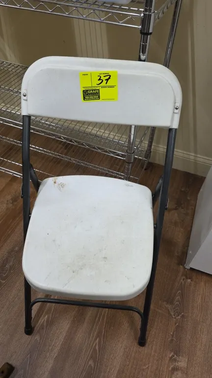 Poly folding chair. Features a white molded plastic seat and contoured backrest mounted on a folding tubular metal frame.