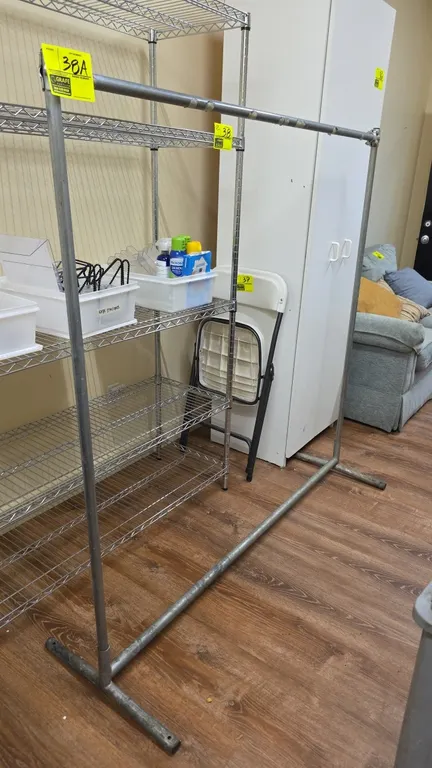 Metal clothes rack. Features tubular metal frame construction with single top hang rail and bottom crossbar. 5' x 5'. Note: Wire shelving and surround