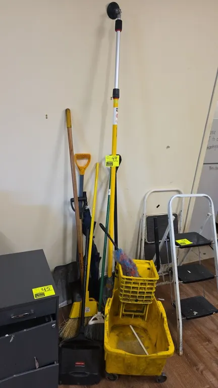Assorted cleaning supplies. Includes yellow poly mop bucket with wringer on casters, Rubbermaid upright dustpan, brooms, shovel, duster, and telescopi