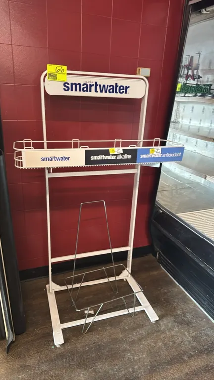 Smartwater metal display merchandiser. Features branded Glacéau Smartwater header sign, wire basket display shelf with product channel labeling, and w