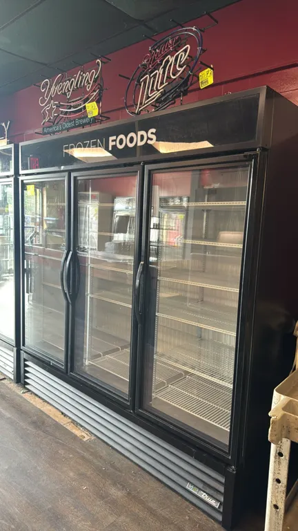 True GDM-72F-HC-TSL01 3-door glass door display freezer. Features backlit 'Frozen Foods' header sign, adjustable wire shelving, interior LED lighting,