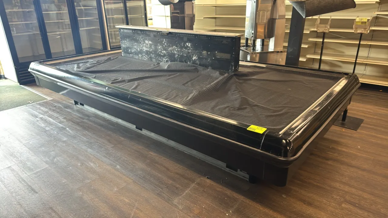 Hill Phoenix refrigerated produce display island. Features center air discharge column, protective perimeter bumpers, and black interior deck matting.