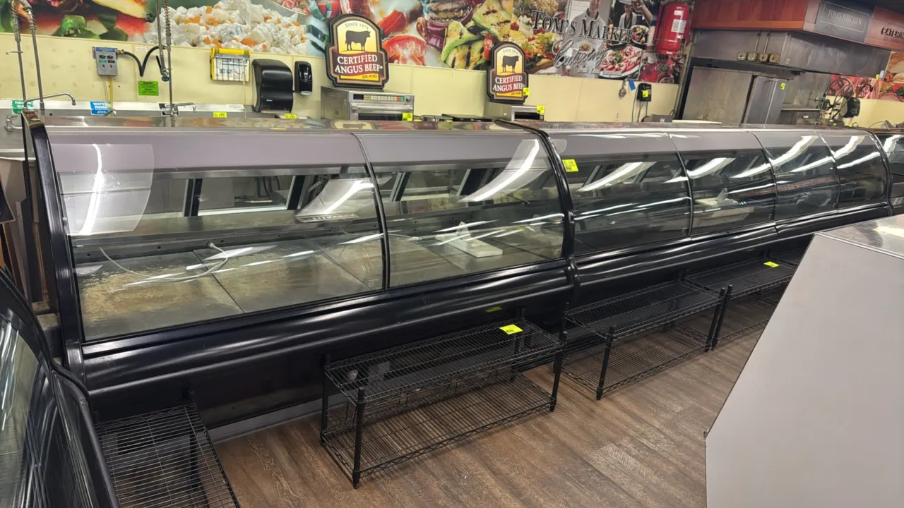 Hill Phoenix curved glass deli service case. Features gravity coils, rear sliding glass service doors, interior mezzanine shelf, stainless steel rear