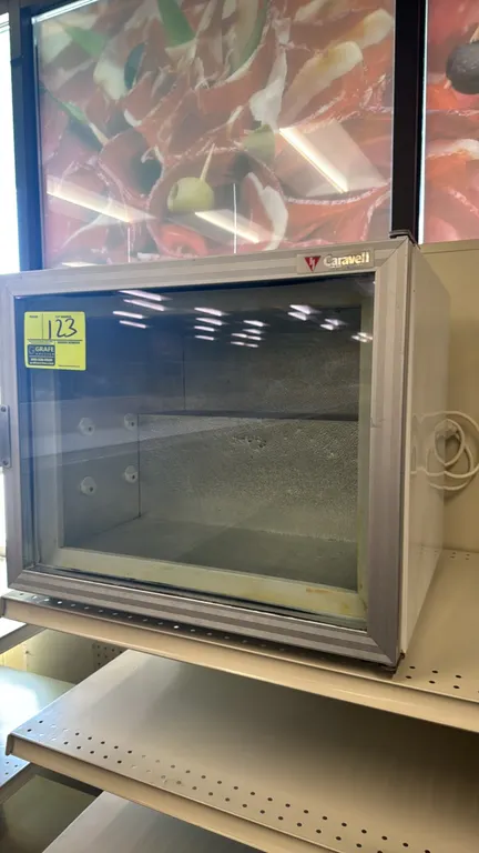 Caravell countertop display mini freezer. Features single hinged glass display door, aluminum door frame, and textured aluminum interior with shelf br
