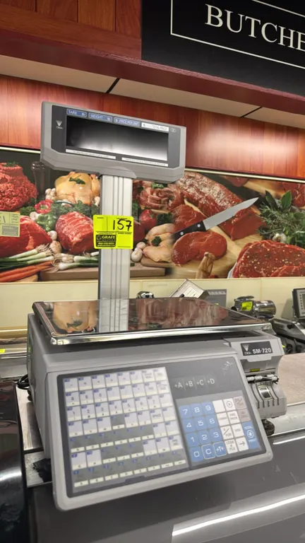 Digi SM-720 30 lb electronic computing scale. Features integrated label printer, raised pole customer display, preset keypad, and stainless steel weig