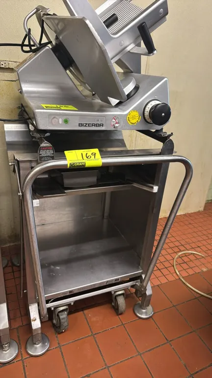 M&E Mfg Face to Face Deli Buddy stainless steel portable slicer stand. Features tubular push handle, slide-out shelf, open lower storage compartment,