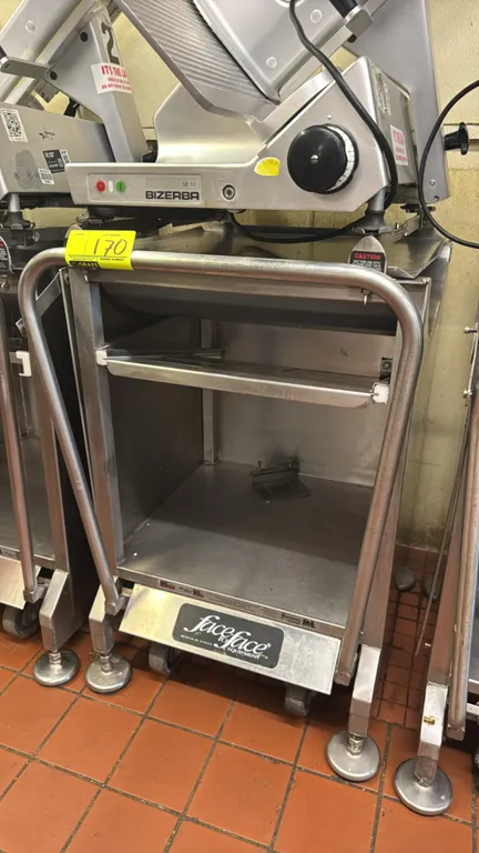 M&E Mfg. Face to Face Deli Buddy stainless steel portable slicer stand. Features tubular push handle, slide-out mid shelf, and open lower storage comp