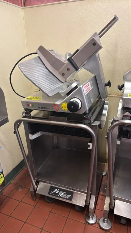 Bizerba SE 12 deli slicer. Features stainless steel construction, gravity-feed carriage, slice thickness adjustment dial, and blade guard. Includes st