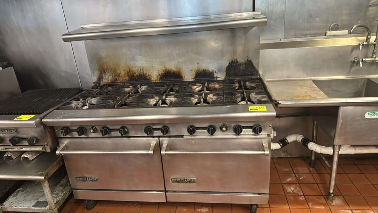 American Range stainless steel 10-burner gas range. Features (2) bake ovens, cast iron burner grates, and stainless steel overshelf. 60"W. Gas powered