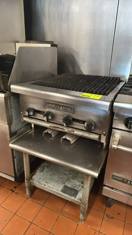 American Range 24" 4-burner gas charbroiler with equipment stand. Features stainless steel construction, cast iron cooking grates, 4 manual burner con