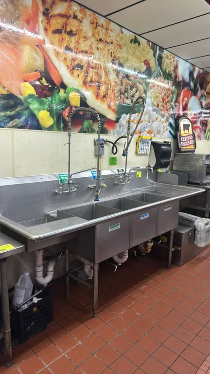 Stainless steel 3-compartment sink. Features left and right drainboards, (2) pre-rinse spray assemblies, scrap basket, and DEMA Duo-Feed chemical disp
