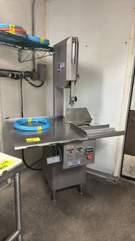 Biro 1433 stainless steel meat saw. Features sliding table carriage, stationary table, thickness gauge plate, blade guard, and includes (4) extra Kasc