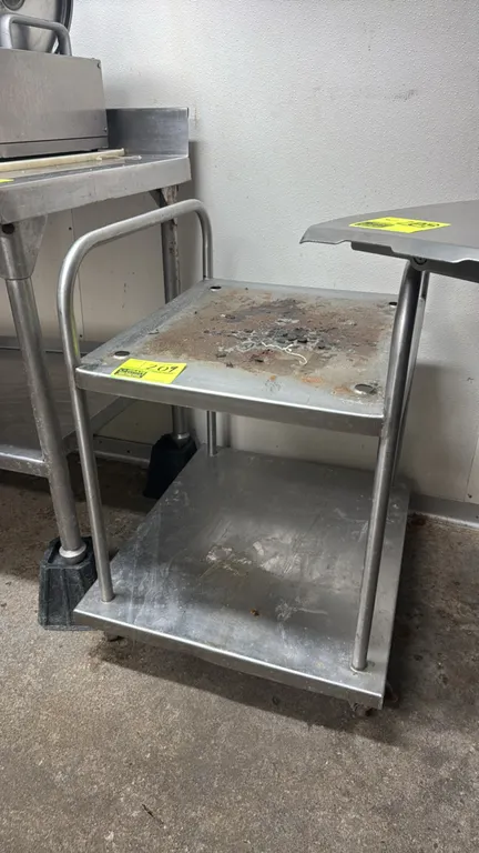 Stainless steel portable equipment stand. Features tubular side handles, lower solid shelf, and equipment mounting holes on top. 21" x 24". Mounted on