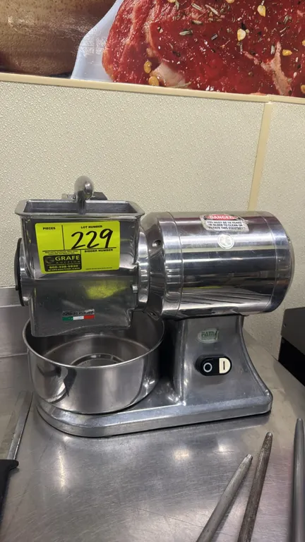 2010 Fama Industrie FGSM15 electric cheese grater. Features polished casing, top feed hopper with pressure handle, toothed grating drum, and stainless