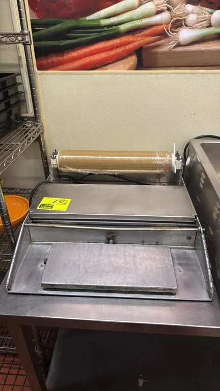 Heat Seal aluminum single roll film wrapper. Features single roll capacity, heated seal plate, and cut-off bar. Electrical: 115V.