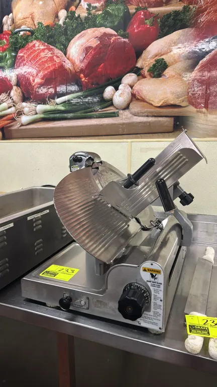 Globe electric meat slicer. Features stainless steel construction, top-mounted knife sharpener, gravity feed carriage with pusher, and slice thickness
