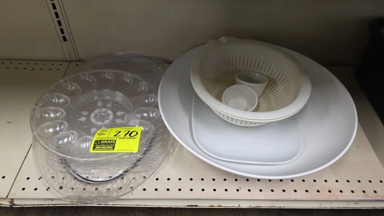 Assorted kitchen and serving ware. Includes clear plastic deviled egg tray, clear textured serving platters, white plastic colander, large white servi