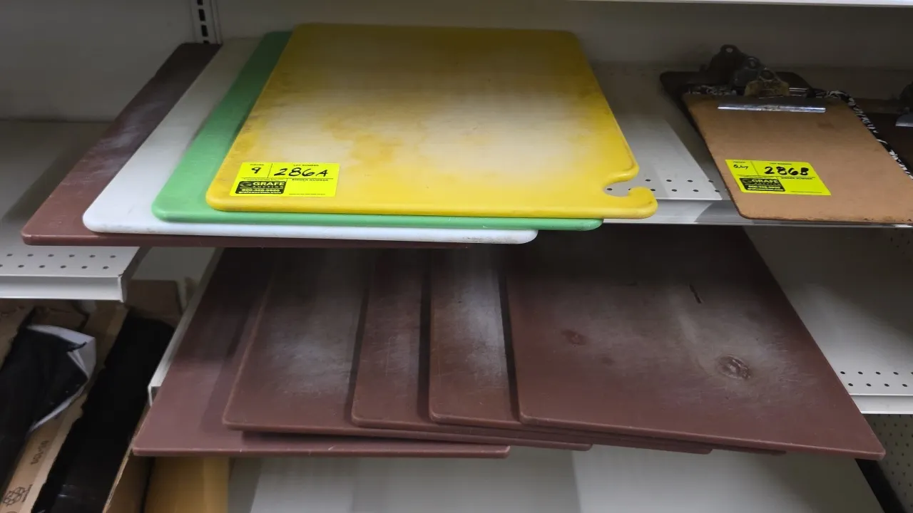 Polyethylene cutting boards. Features assorted colors including brown, green, yellow, and white, and an integrated hanging hook on the yellow board. 1