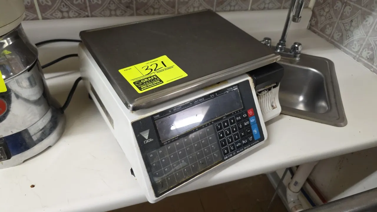 Digi SM-110 TYPE B+ digital computing scale with integrated printer. Features a stainless steel weighing platter, digital display, and preset keypad.