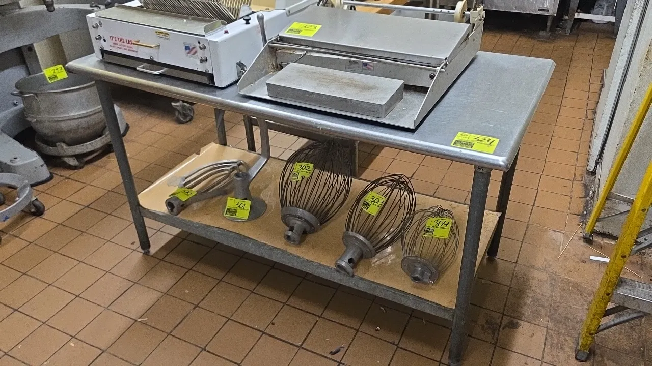 Stainless steel work table. Features a stainless steel top, galvanized undershelf, and galvanized legs with adjustable bullet feet. 5'L. Contents not