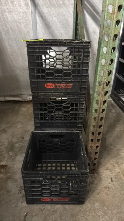 Poly milk crates. Features black molded plastic construction, integrated side carry handles, vented sides, and grid bottom. Stackable design. Hood bra