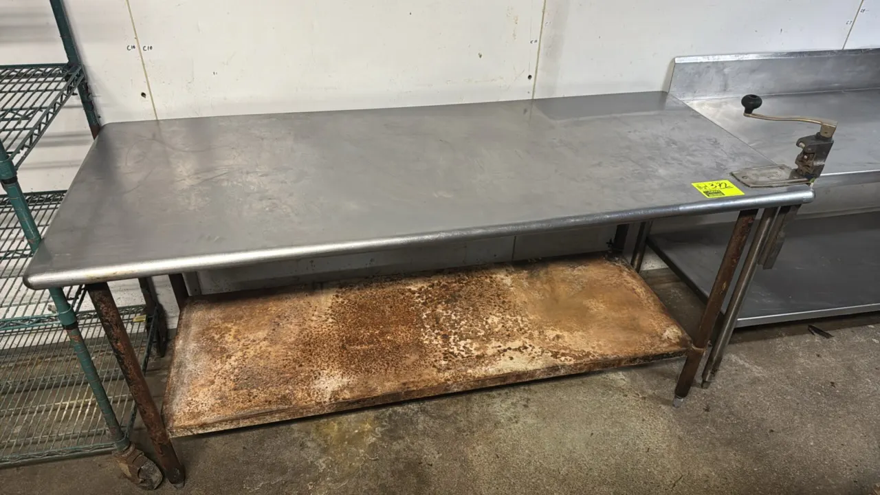 Stainless steel work table with mounted Edlund manual can opener. Features a galvanized undershelf. 72" x 30". Note: Undershelf and legs show heavy ru