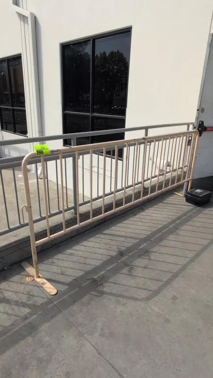 Metal crowd control barrier. Features tubular steel construction, vertical pickets, and interlocking side hooks. Dimensions: 96"W x 40"H. Supported by