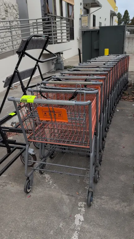 Metal shopping carts. Features orange coated wire baskets, gray tubular metal frames, folding child seats with safety straps, lower wire storage trays